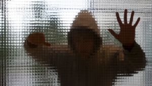 Många män utsetts för våld men berättar aldrig om det Anonym ung beter sig våldsamt bakom en glasvägg.