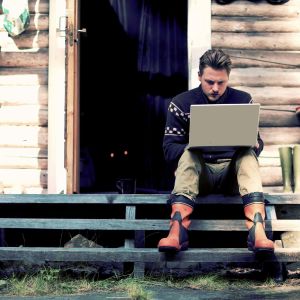 Mies istuu portailla läppäri sylissä.