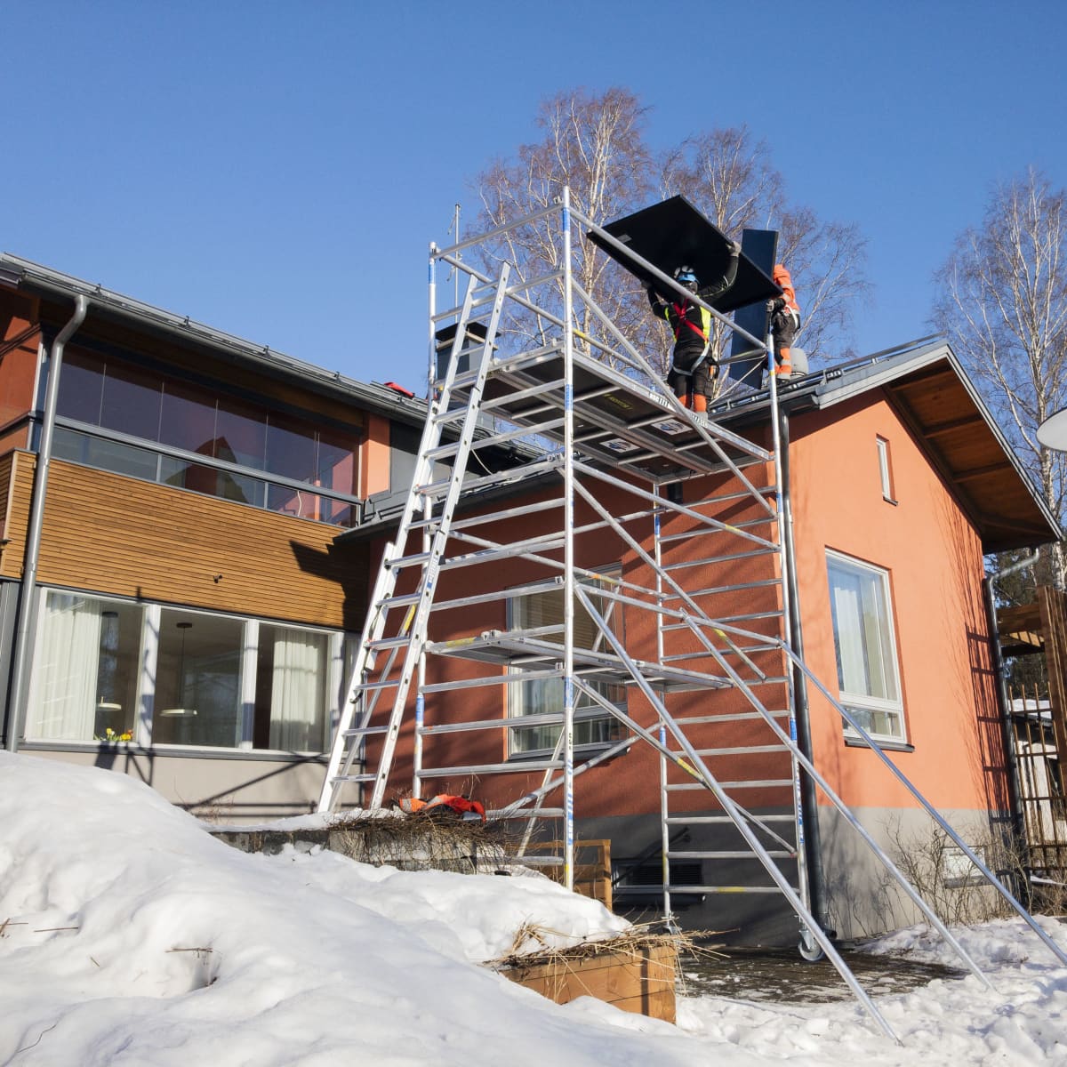 Aurinkopaneeleja nostetaan omakotitalon katolle.