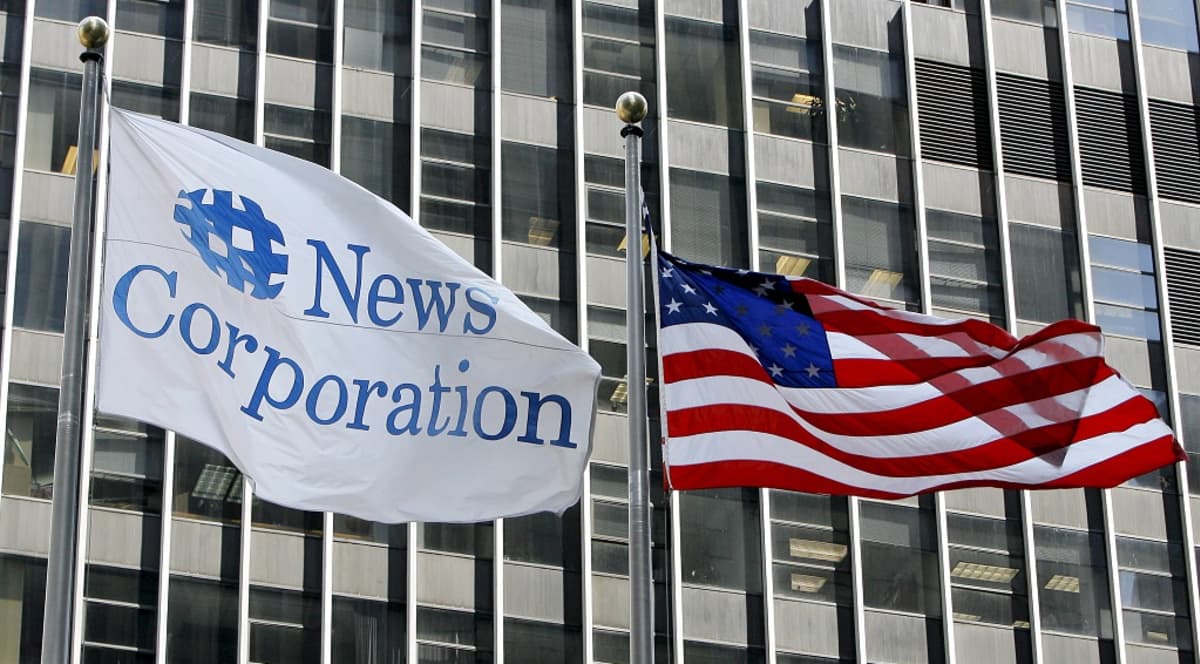 Kuvassa vasemmalla salossa liehuu lippu, jossa lukee News Corporation. Sen vieressä oikealla puolella on Yhdysvaltain lippu. 