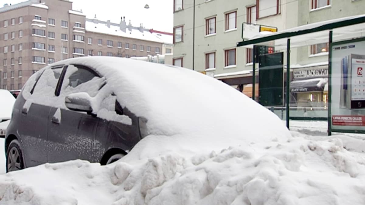 Lumeen peittynyt auto.