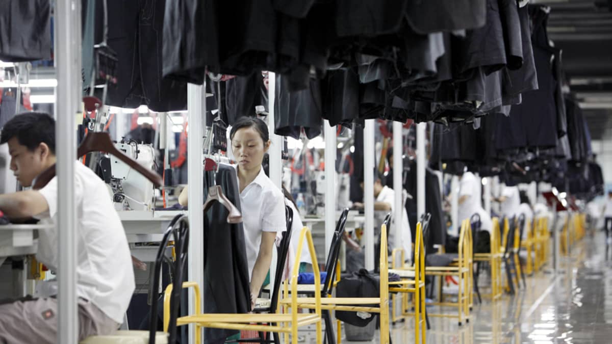 Kiinalaiset ompelijat työskentelevät vaatetehtaan liukuhihnalla.