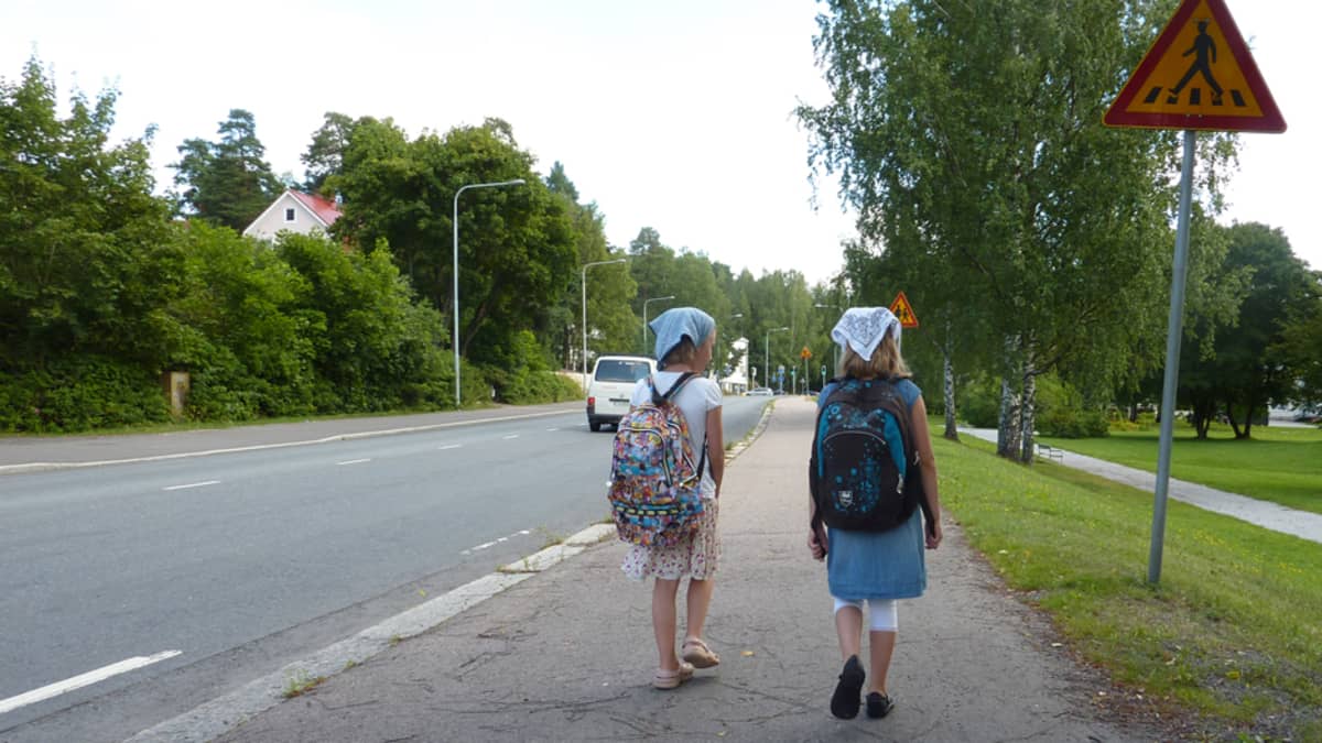 Kaksi reppuselkäistä tyttöä koulutiellä