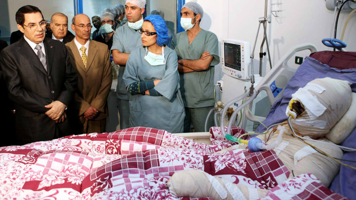 Tunisian presidentti Zine El-Abidine Ben Ali vierailee itsensä tuleen sytyttäneen Mohamed Bouazizin sairaalahuoneessa.