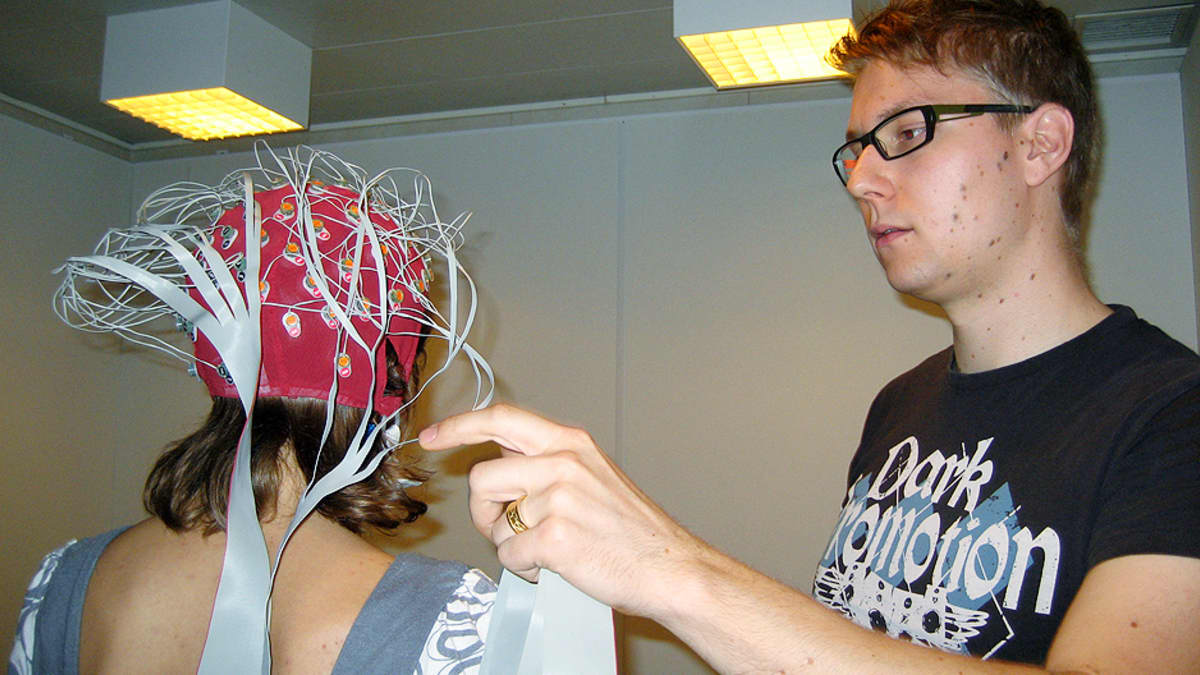 Kaksi ihmistä testaa aivojen reagointia musiikkiin EEG-laitteen avulla.