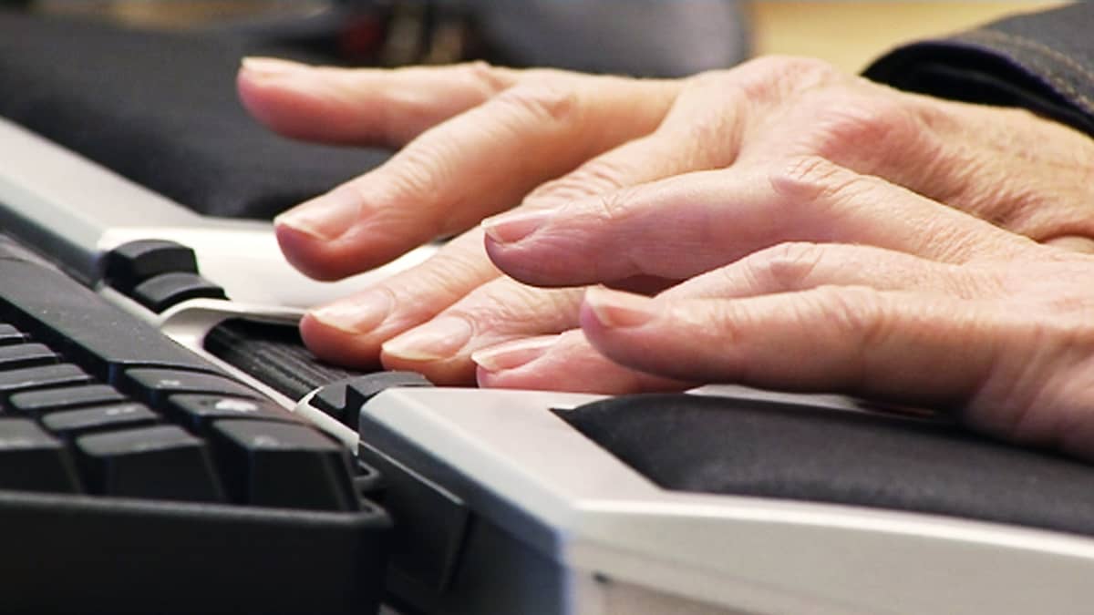 Henkilö kirjoittaa tietokoneella, lähikuva käsistä näppäimistöllä.