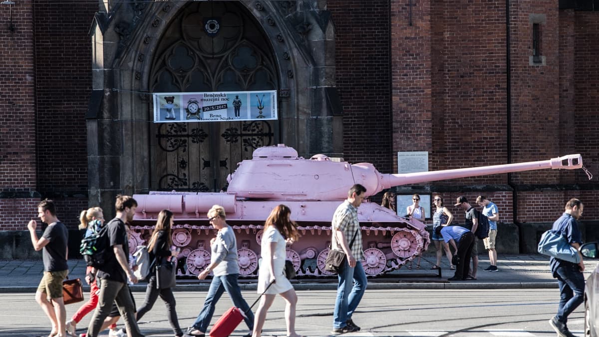 Vaaleanpunainen panssarivaunu ja ohi käveleviä ihmisiä.