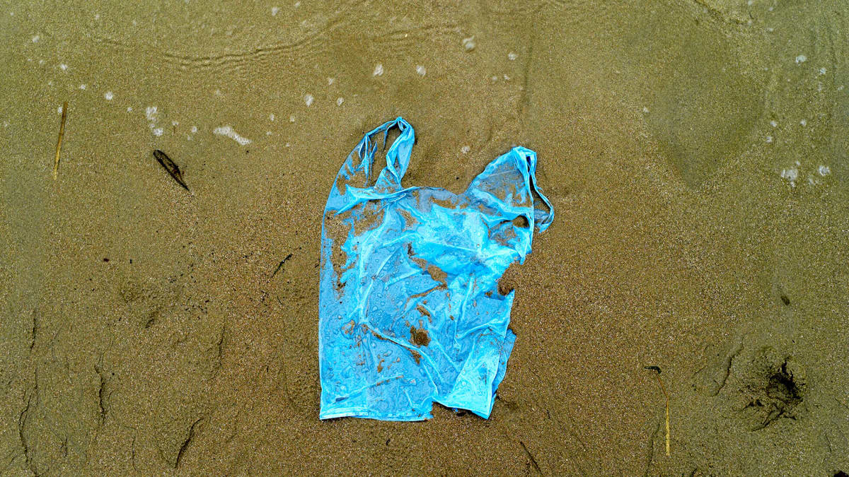 Muovikassi on huuhtoutunut rantahiekalle.