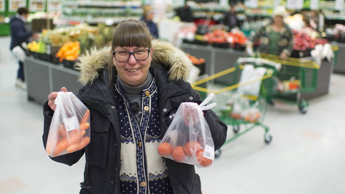 Hannele Kaskinen pitelee kahta hedelmäpussia kaupassa.