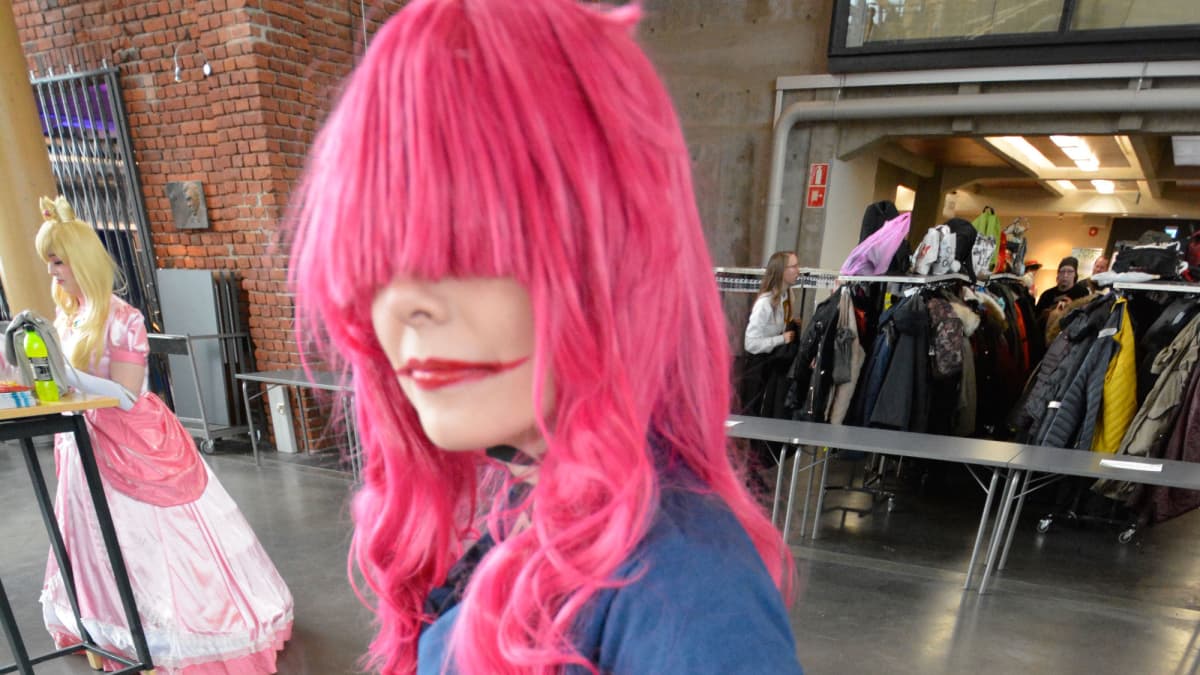 Laura Lipponen on pukeutunut Gatchaman Crowds- pelin Berg Katzen siniseen pukuun ja pinkkiin peruukkiin.