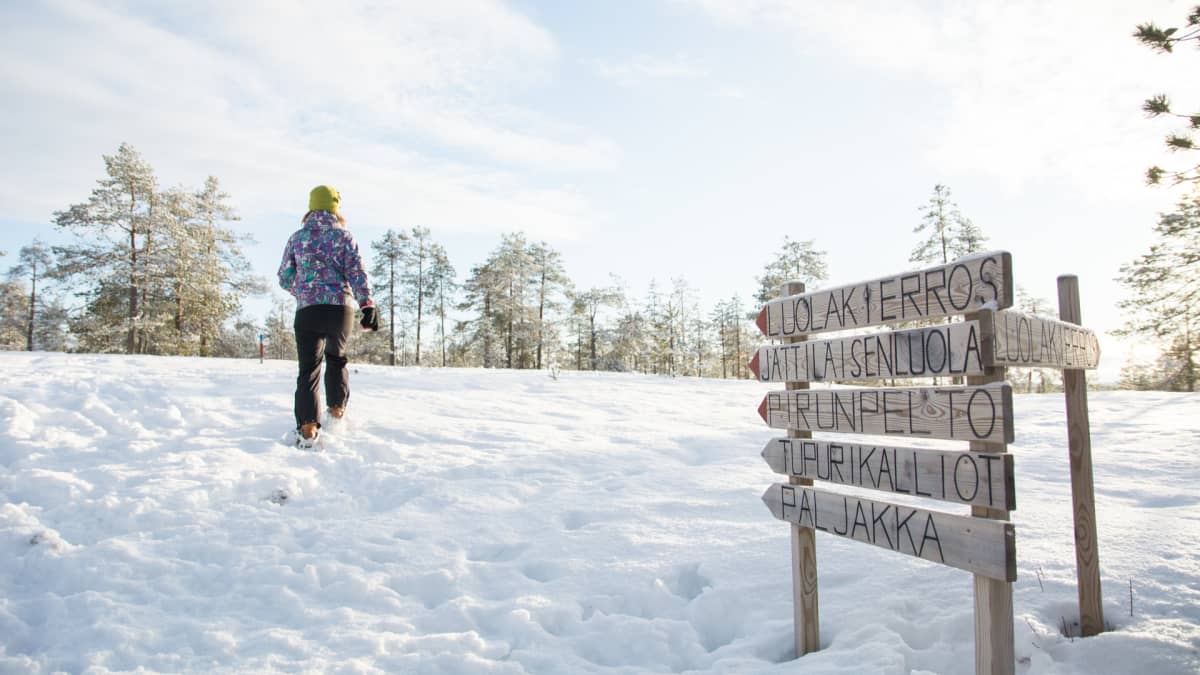 Nainen kävelee lumikengillä.