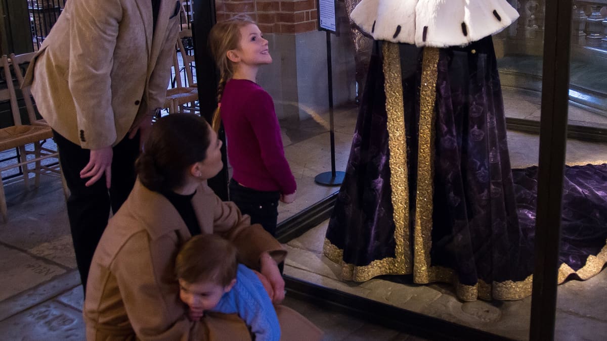Ruotsin kruununprinsessa Victoria, prinsessa Estelle ja prinssi Oscar tutustumassa näyttelyyn Tukholman tuomiokirkossa, Storkyrkanissa. Oppaana on pappi Ulf Lindgren.