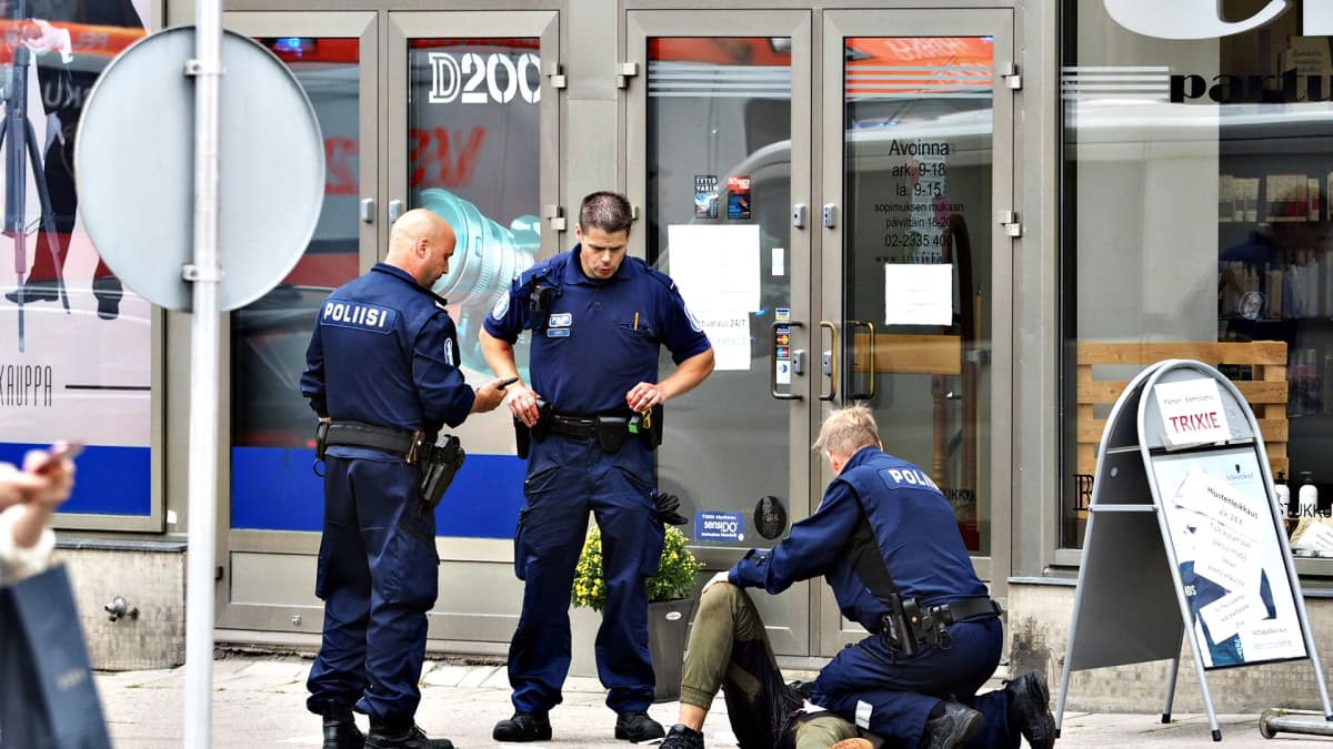 Kuva Turun puukottajasta 18. elokuuta 2017. Poliisit ovat ympäröineet maassa makaavan miehen.