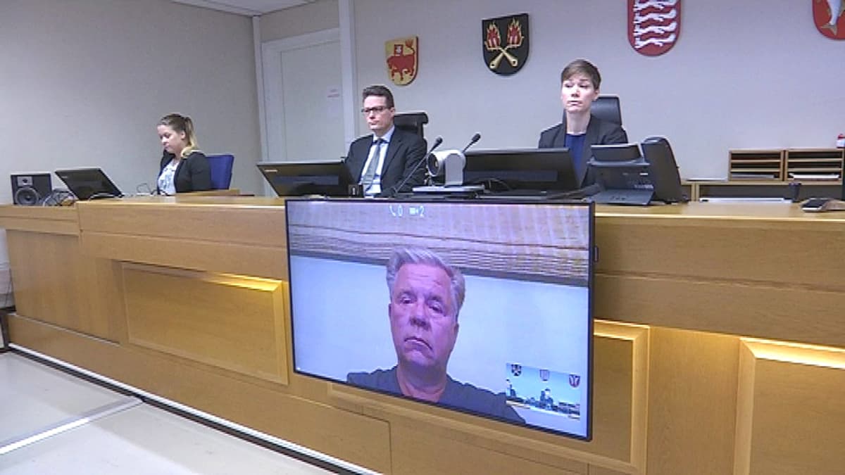 Kuva oikeussalista, jossa tuomarit kuuntelevat vastaajaa videoyhteyden kautta
