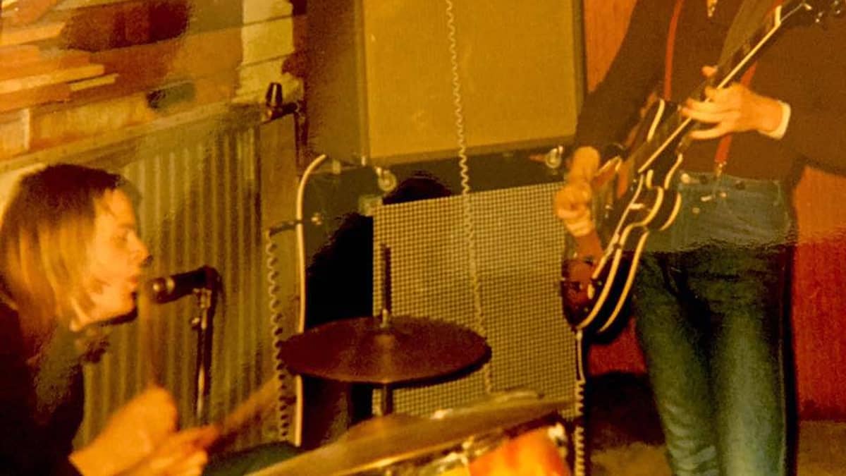 1970-luvun alku, bändin kaksi jäsentä soittaa vanhassa valokuvassa, Pelle Miljoona rummut, Hapa Tyni, kitara