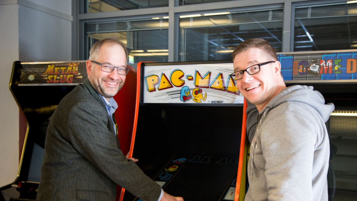 Taloustieteen professori Panu Kalmi ja pelitutkija Olli Raatikainen ikonisen Pac-Man -pelin äärellä.