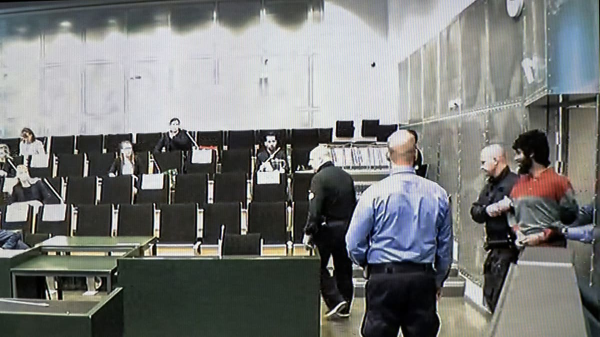 Vartijat tuovat Turun elokuisen puukkoiskun tekijän Abderrahman Bouananen Turun vankilan saliin.
