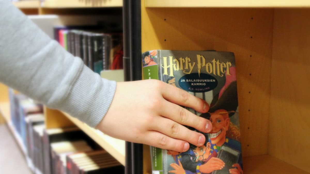 Käsi nostaa kirjaston hyllystä Harry Potter -kirjan.