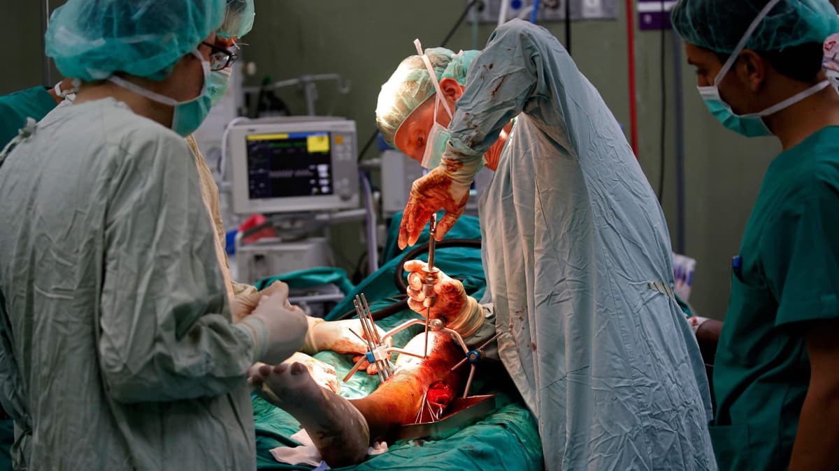 Kirurgi poistaa luotia palestiinalaisen miehen jalasta.
