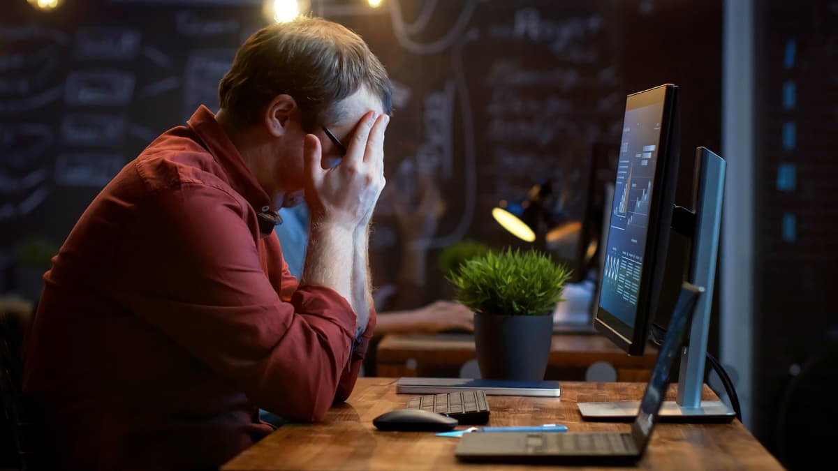 mies ahdistuneena tietokoneen edessä
