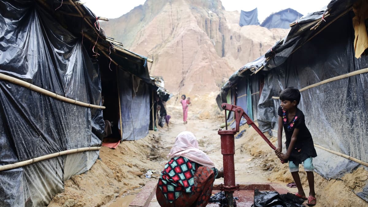 Rohingya-tyttö pumppaa vettä kaivosta telttaleirissä.