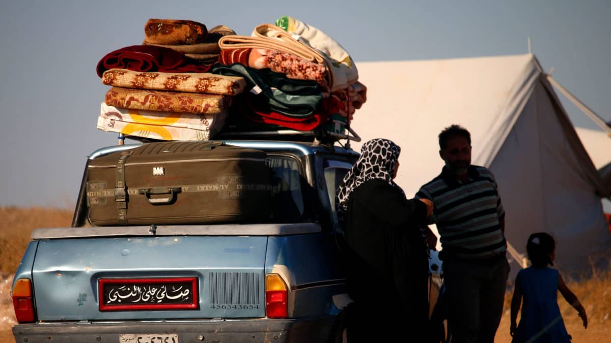 Syyrialaisia pakolaisia seisomassa täyteen pakatun autonsa vieressä lähellä Jordanian rajaa.