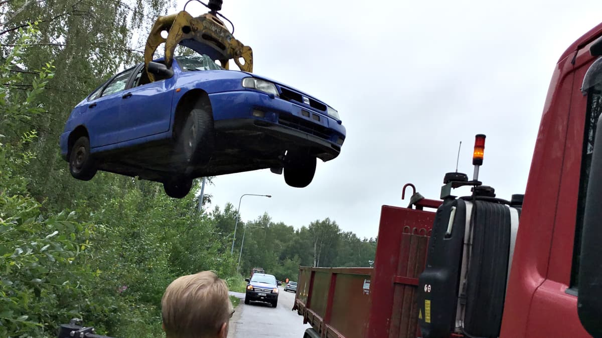 Hylättyä romuautoa kuljetetaan tienvarresta pois purkaamolle kierrätystä varten.