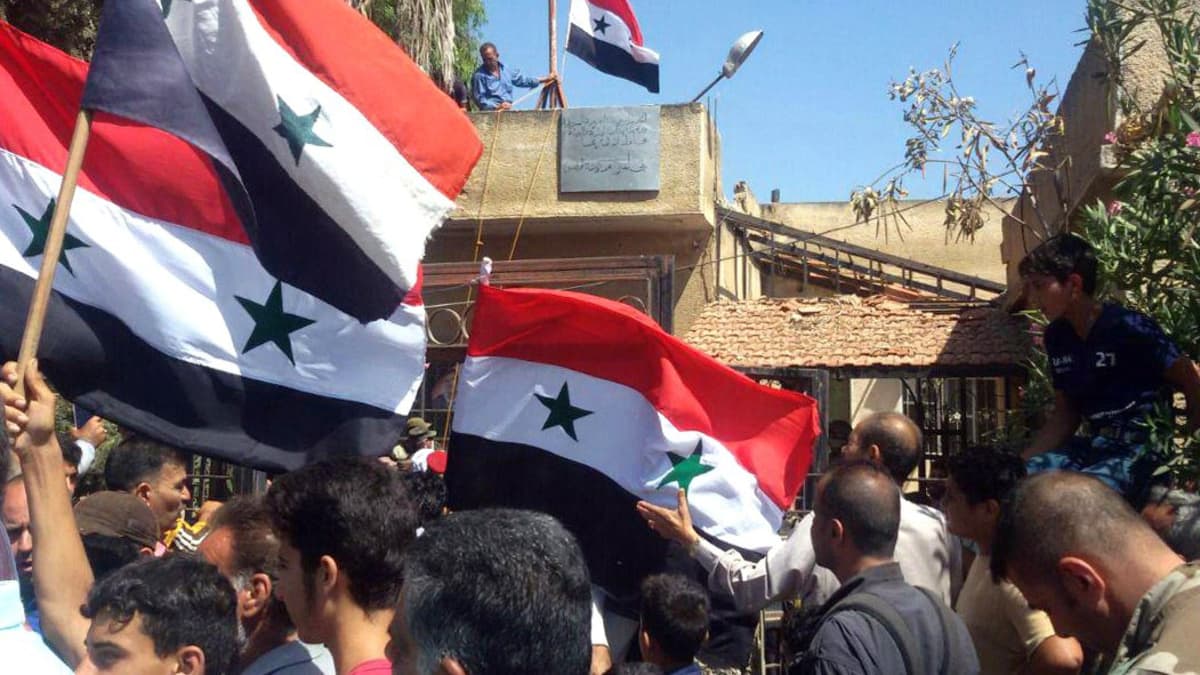Syyrialaiset miehet heiluttavat Syyrian lippuja Tafaksen kaupungissa, Daraan maaseudulla.