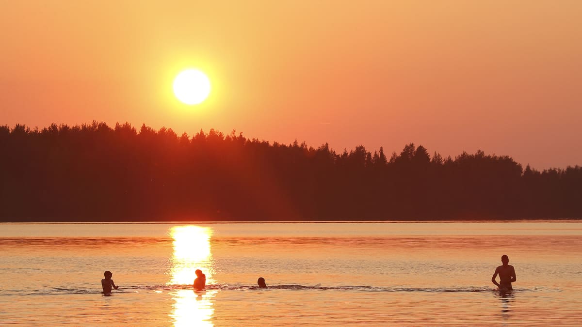 ihmisiä uimassa auringonlaskussa