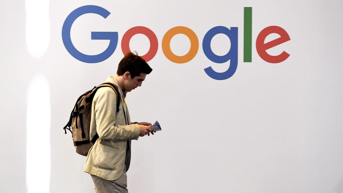 Mies kävelee Googlen logon edessä.