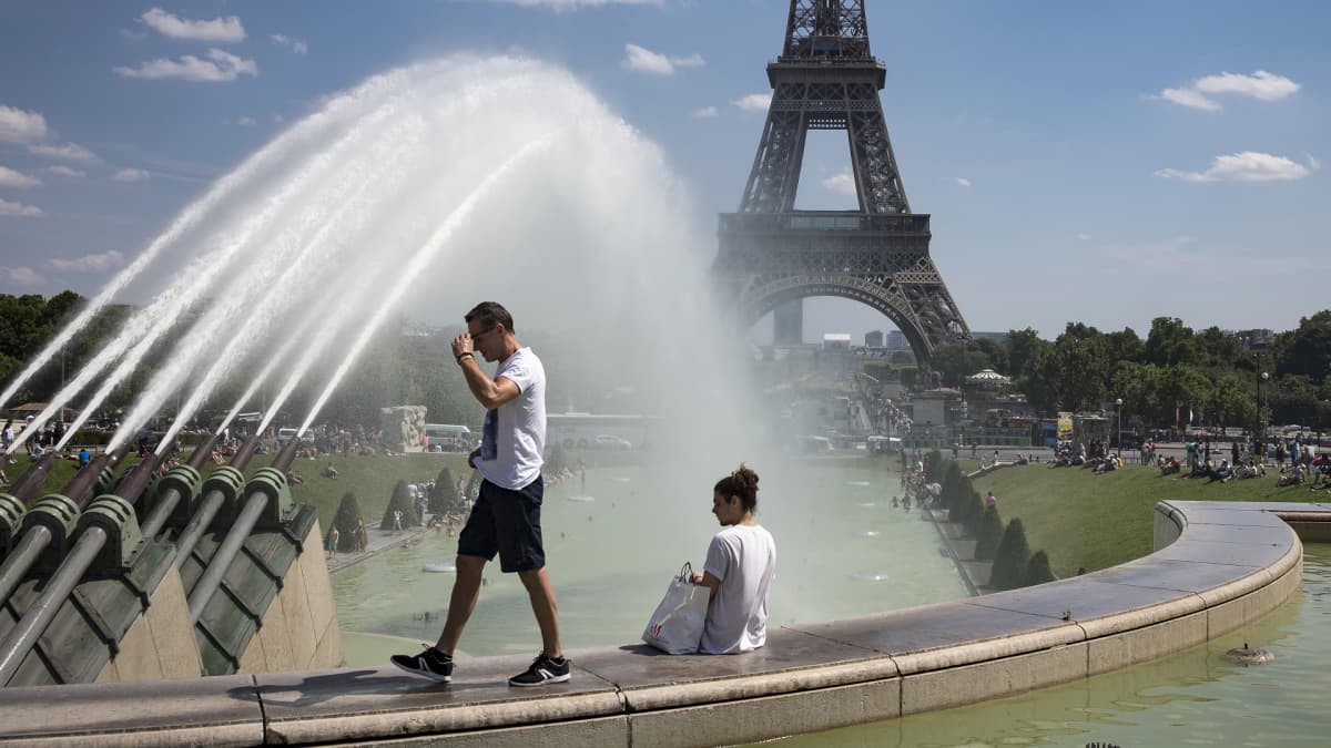 mies kävelee ja nainen istuu Eiffel-tornin edessä.
