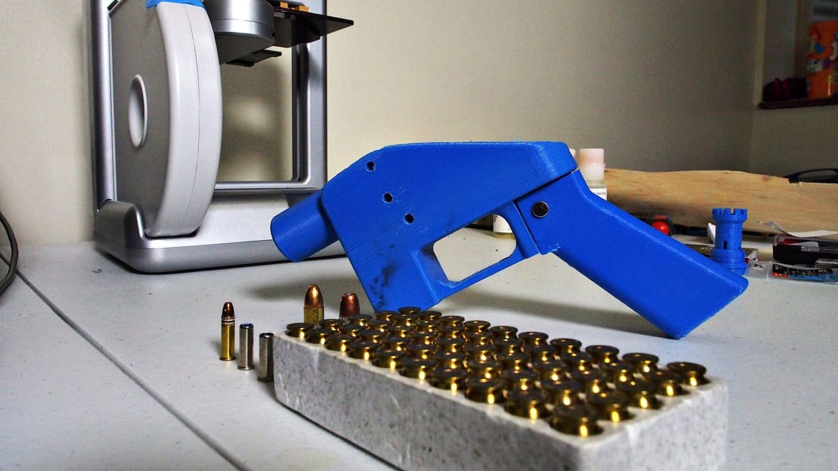 Kuvassa pistoolin edessä on 3D-tulostin, jolla pistoolin osat on valmistettu.