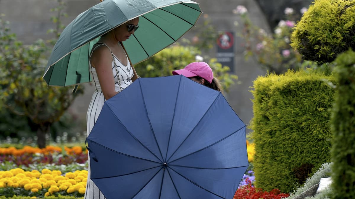 Ihmiset suojautuivat paahtavalta auringolta sateenvarjoin Bargassa, Portugalissa perjantaina.