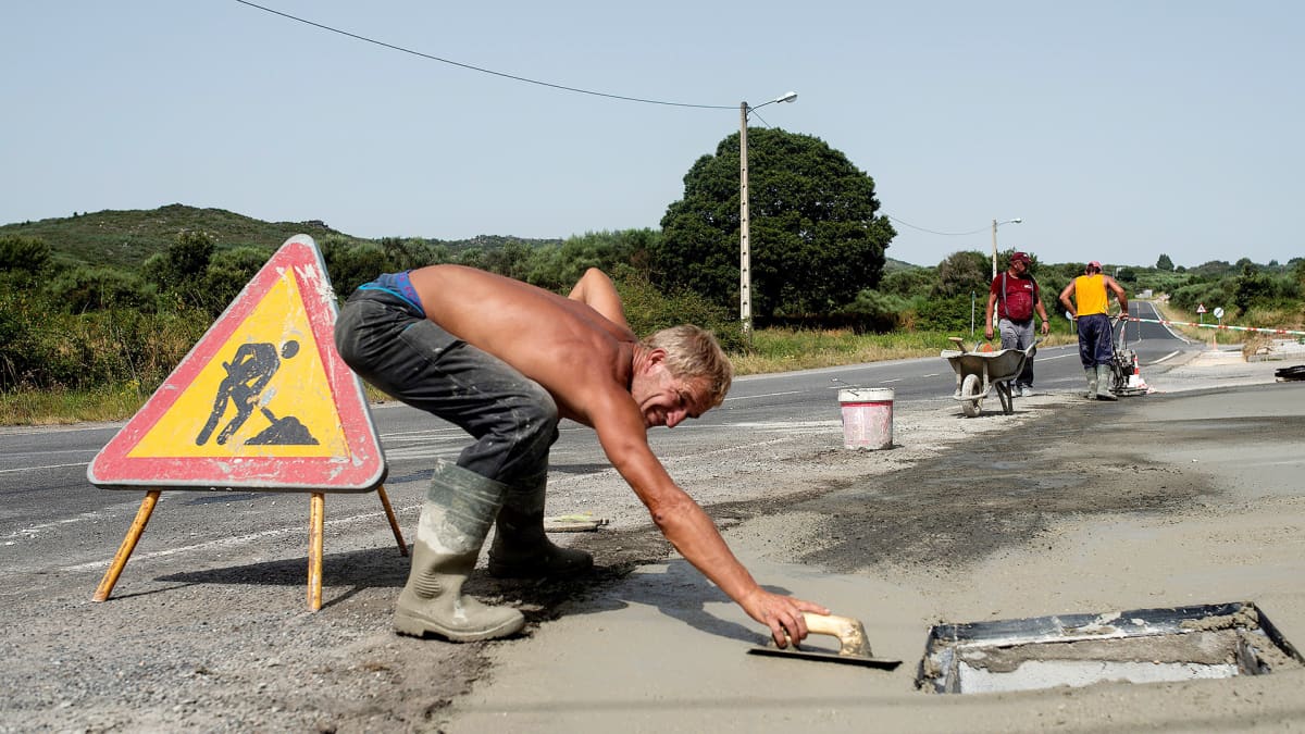 Mies korjaa maantien päällystettä kovalla helteellä Lounais-Espanjassa.