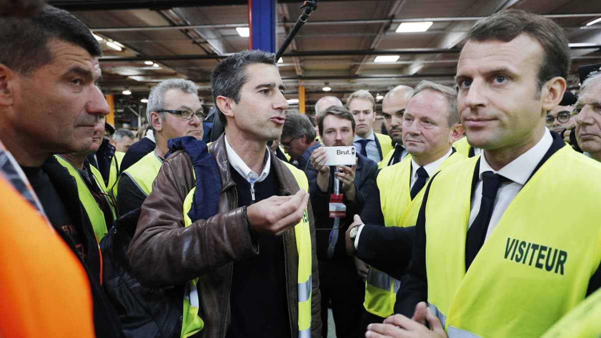 Emmanuel Macron suojaliivissä tehtaalla.