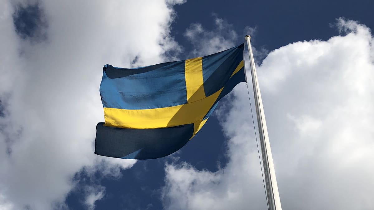 ruotsin lippu liehuu, valkoisia pilviä ja sinistä taivasta