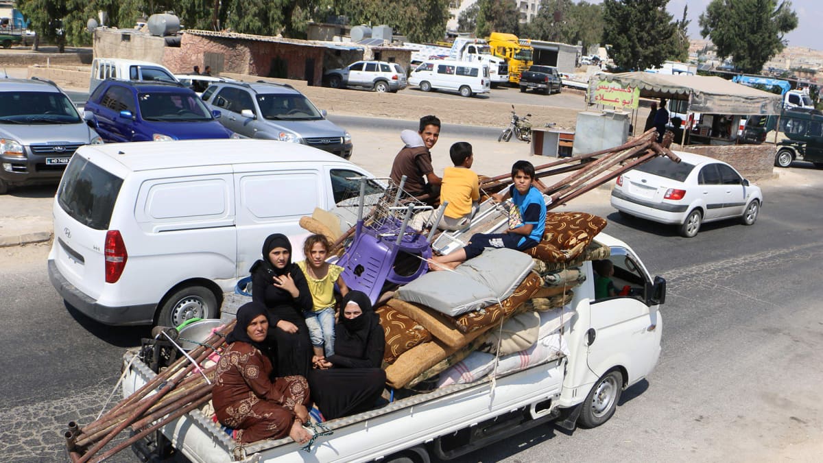 Siviilit pakenevat Idlibin maakunnassa Syyriassa, auton lavalla seitsemän ihmistä, patjoja ja huonekaluja.