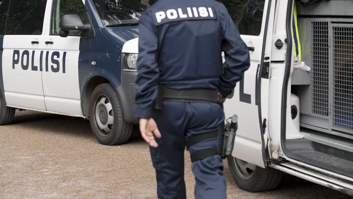 Poliisi poliisiauton edustalla.