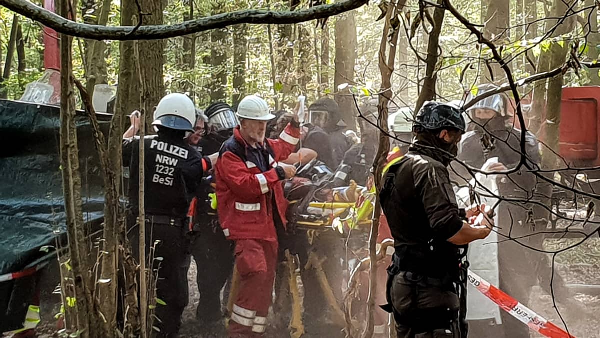 Poliiseja ja ambulanssihenkilökunta auttavat metsässä loukkaantunutta