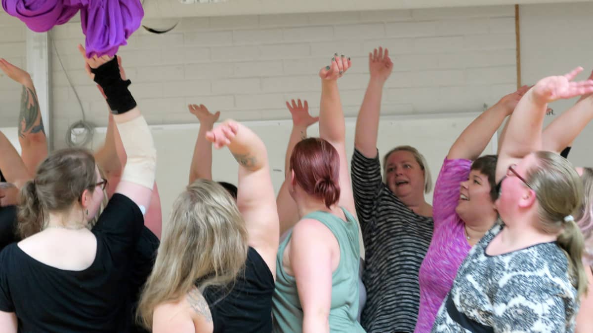 Naisia käsi ylhäällä ryhmässä tanssitunnilla