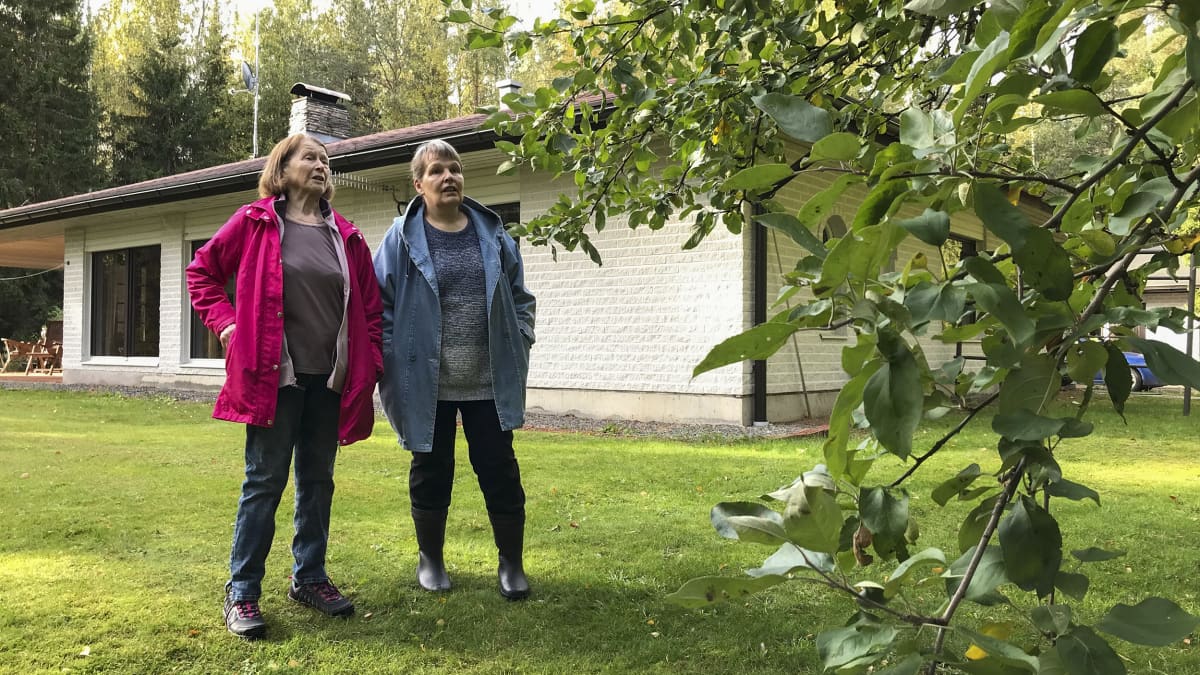 Kaksi naista seisoo puutarhassa.