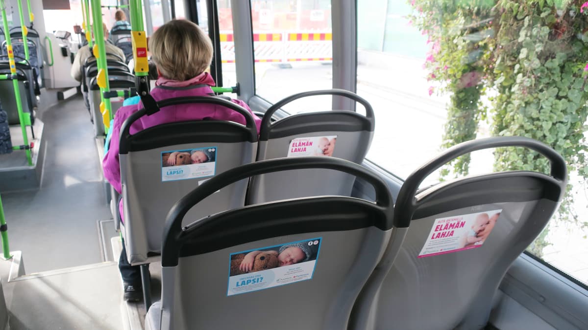 Ovumia Fertinovan mainoksia bussin penkkien selkänojissa.