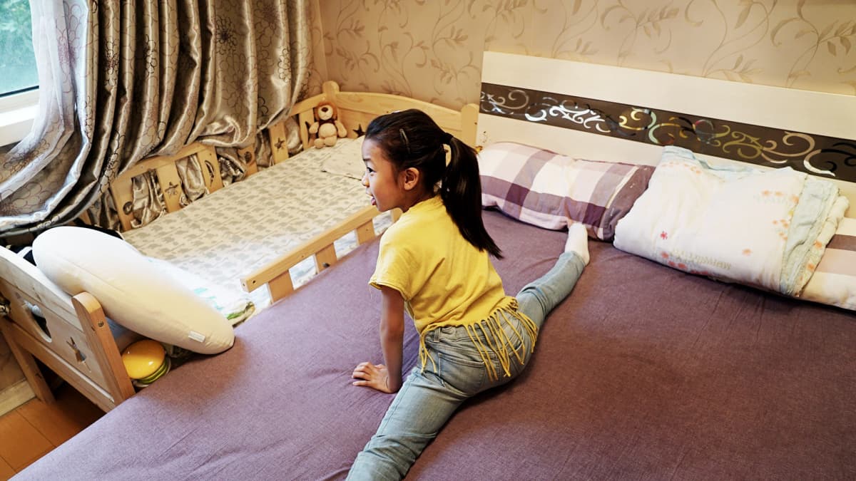 Qiqi taipuu spagaattiin vanhempiensa sängyllä. Vieressä on pikkuveljen sänky.
