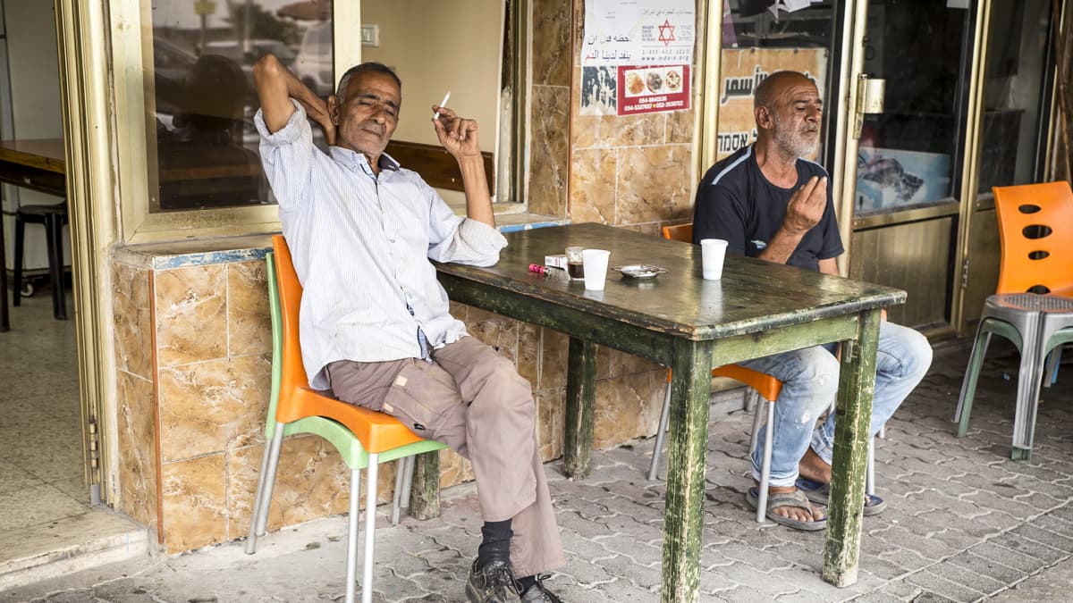kaksi miestä tupakoi katukahvilassa