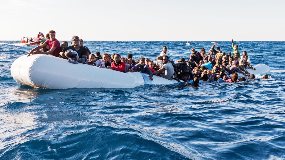 Siirtolaisia kumiveneessä meressä.