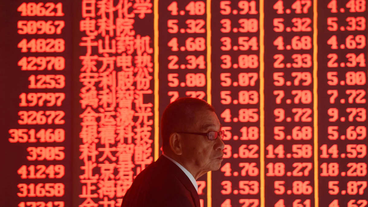 Kiinalainen pörssimeklari pörssikursseja esittävän valotaulun edessä.