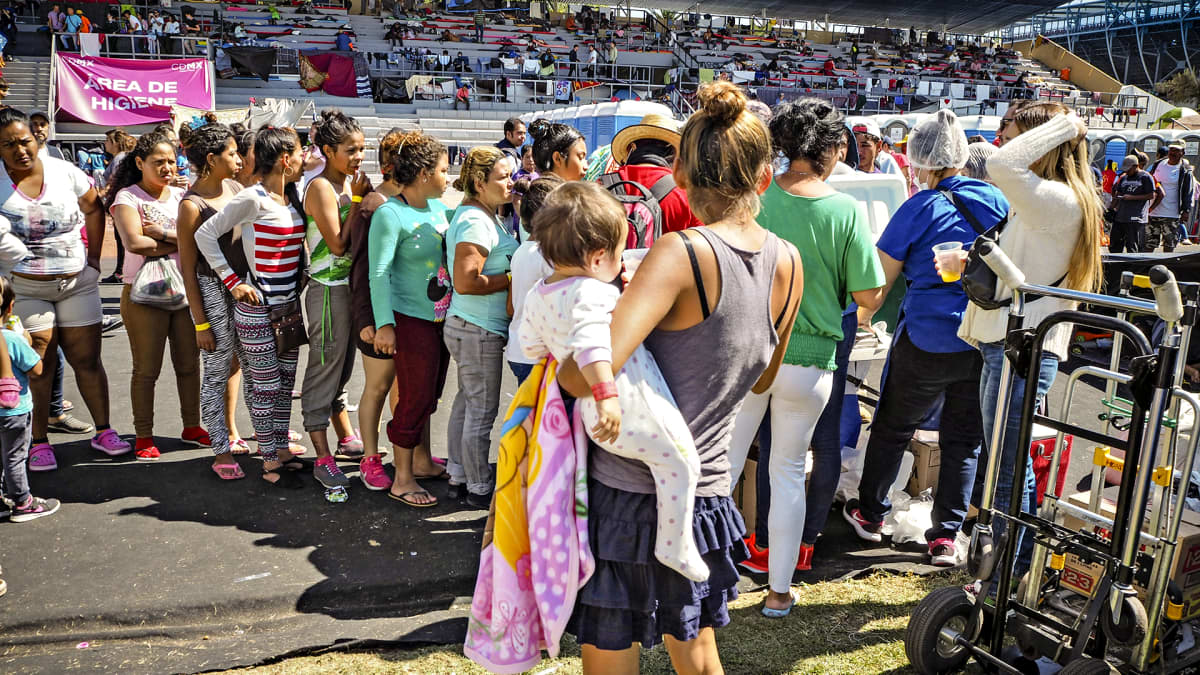 Siirtolaiskaravaanin jäsenet jonottavat juomista urheilustadionilla Méxicossa.