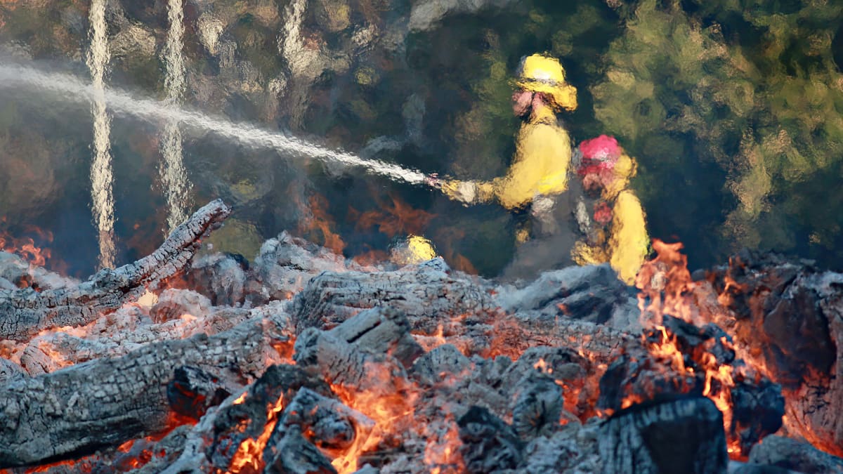 Palomiehet sammuttavat liekkejä pelastusarmeijan leirillä toissapäivänä Malibussa, Californiassa.