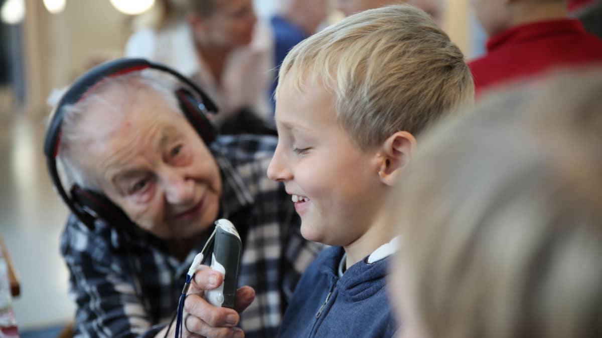 101-vuotias Lydia Haaksalo kommunikoi kakkosluokkalaisen Aatoksen kanssa apulaitteen välityksellä.