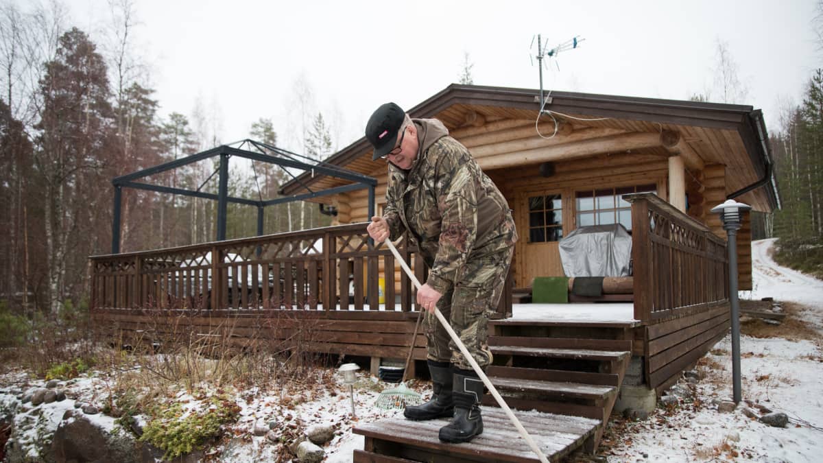 Pekka Hujanen lakaisee mökin portaita.